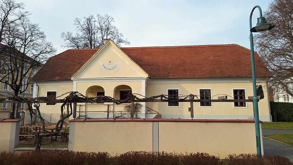 Traditionelles cremefarbenes Gebäude mit rotem Dach, wahrscheinlich ein Gemeindehaus.
