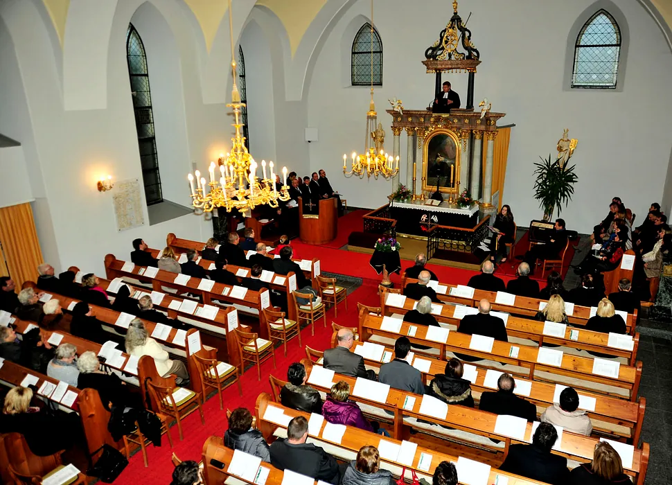 Ein Gottesdienst von oben, Gemeinde und verzierter Altar sichtbar.